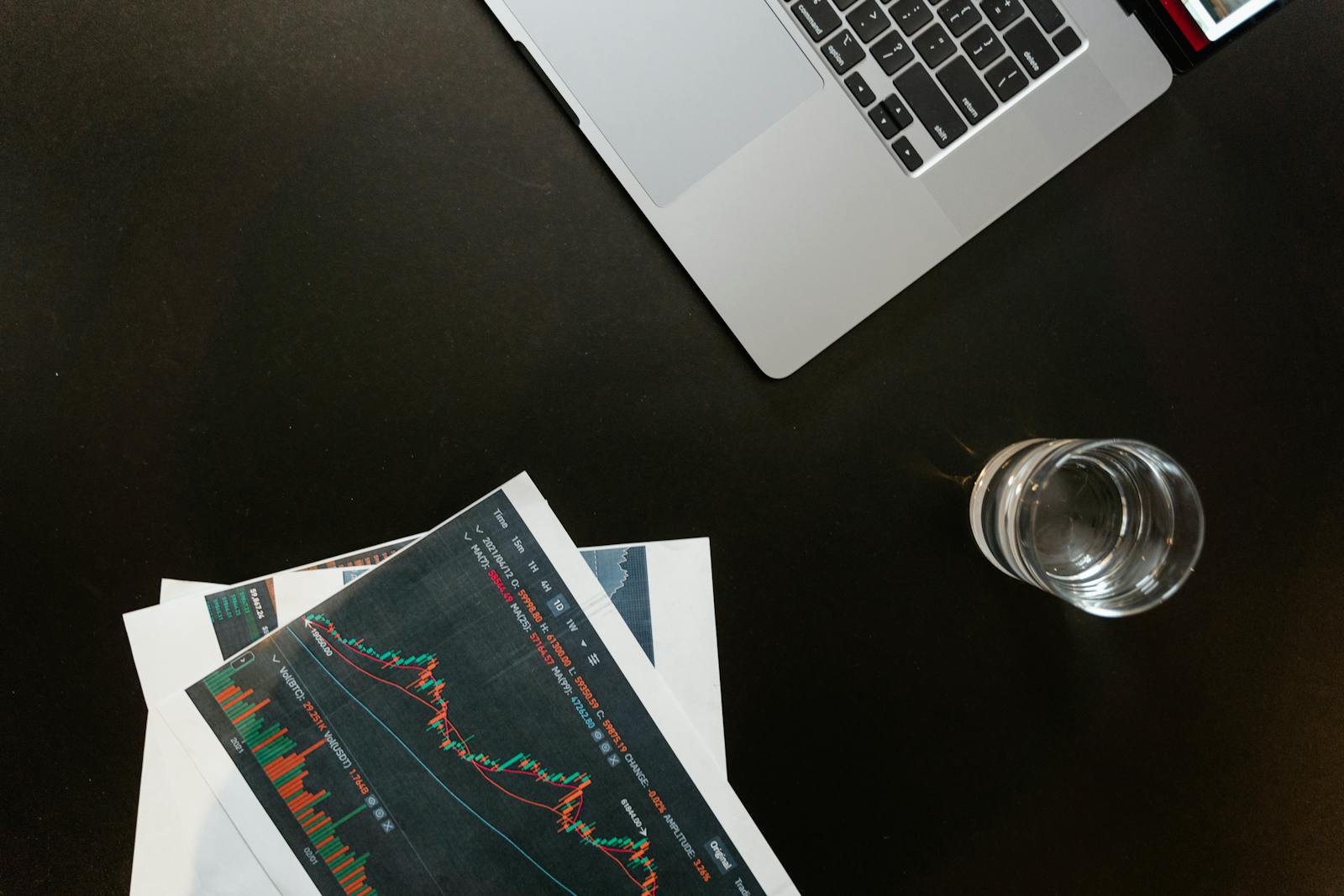 Desk with laptop displaying financial charts and office paperwork, representing RIA billing and revenue operations