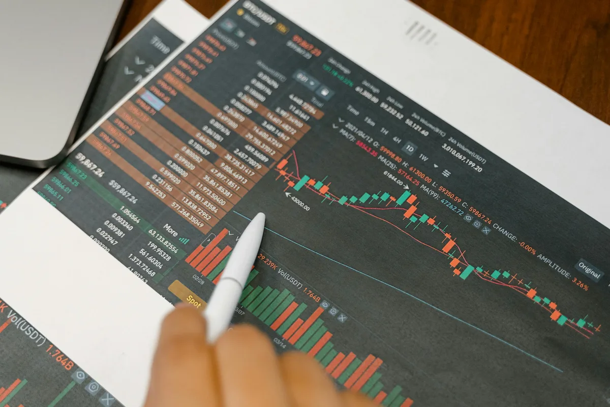 Close up of a person analyzing cryptocurrency graphs on printed charts.