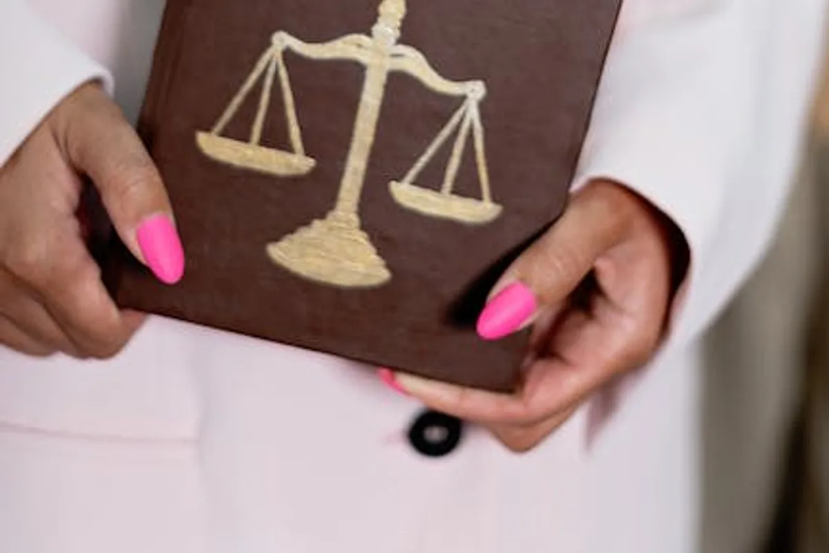 Close-up of a woman holding a law book with scales of justice, emphasizing legal themes.