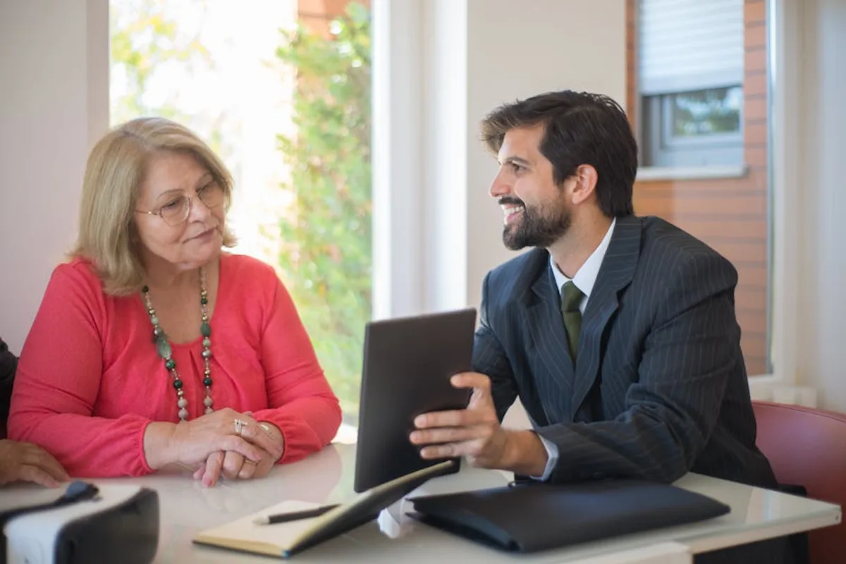 Elderly woman consulting with a realtor about a property deal in a cozy indoor setting.