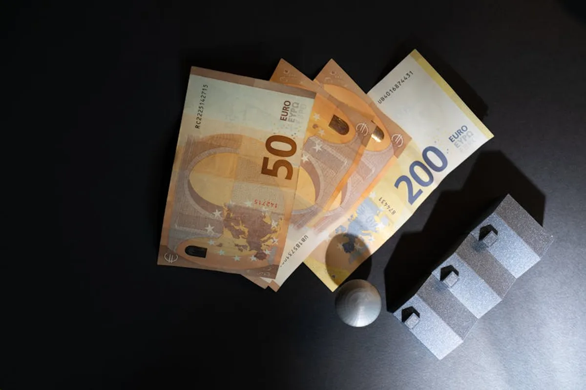 Close-up of Euro banknotes and model houses on dark background symbolizing real estate investment.